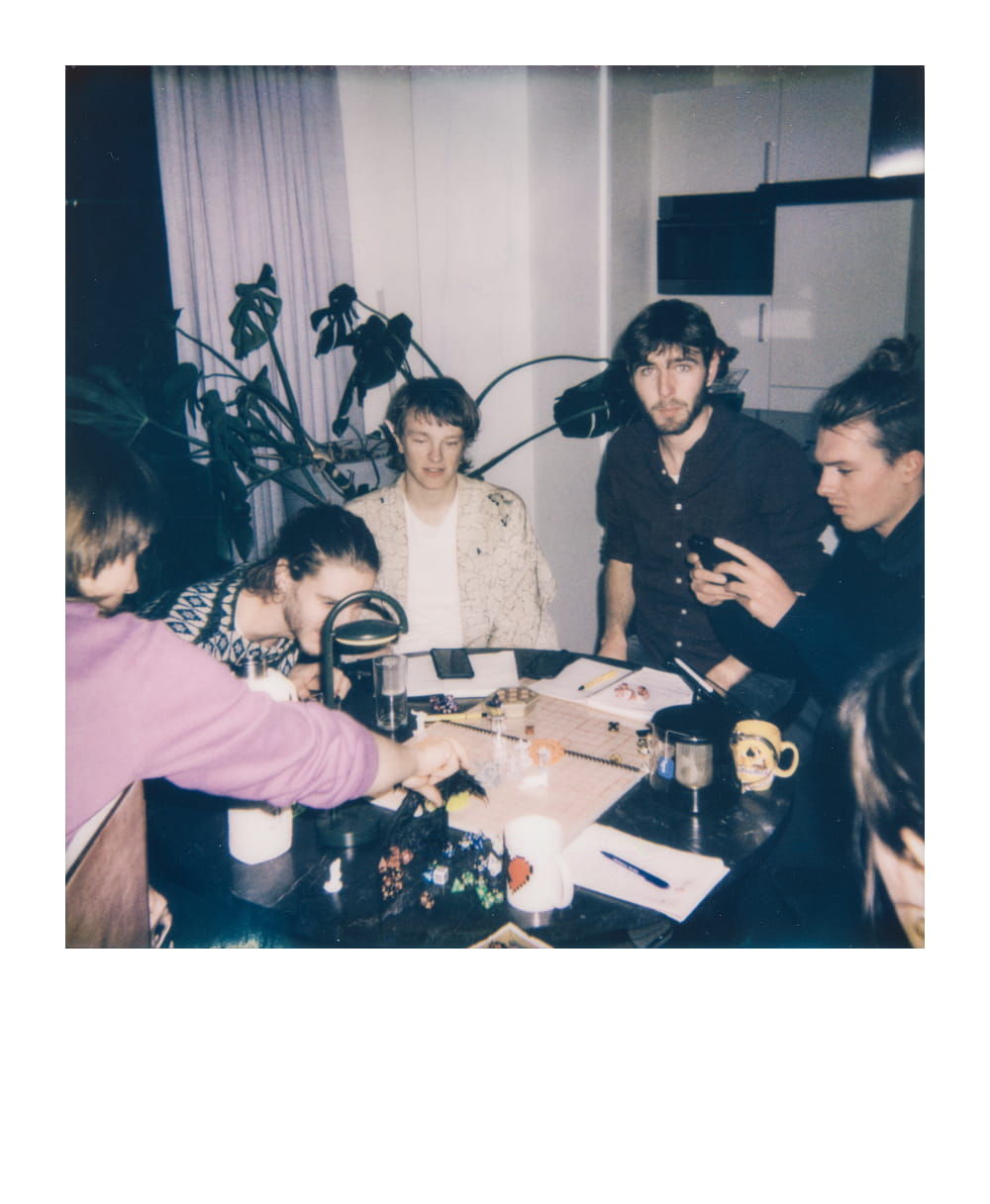 Freundesgruppe spielt Dungeons & Dragons am Tisch mit Würfeln und Charakterblättern